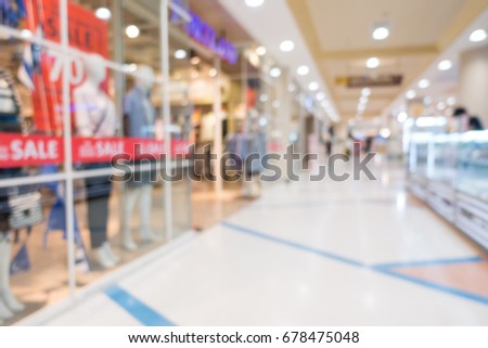 Blurred image of shopping mall and people walking for background usage,  Sale banner  in shop window.