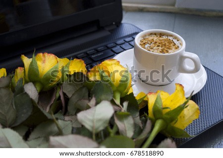 Cup of coffee and roses on laptop