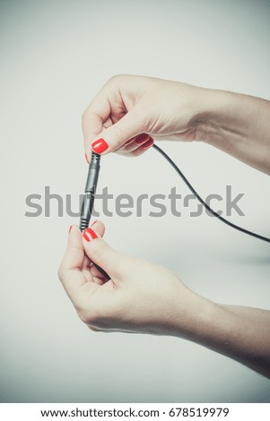 Girl with red manicure connects two audio connectors