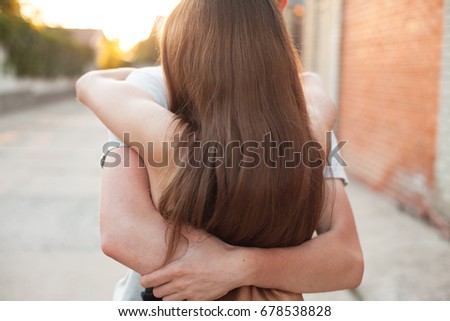 Lovely couple are hugging on the street at sunset. Back view