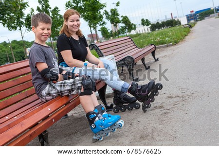Caucasian young boy in roller-skating equipment and a mom are skating on city streets