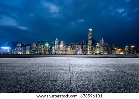 empty brick platform with Hong Kong skyline in background at night.