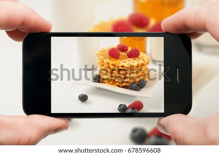 Taking photo of waffles by smartphone. Closeup view of process. File contains clipping paths for smartphone and hands and picture on it