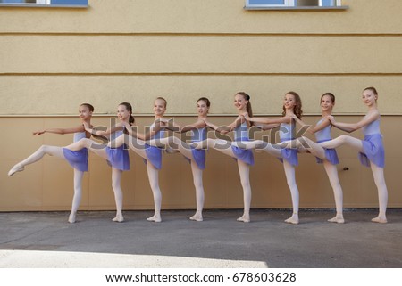 Ballet dancers dancing on street. Young ballerinas on yellow background full length