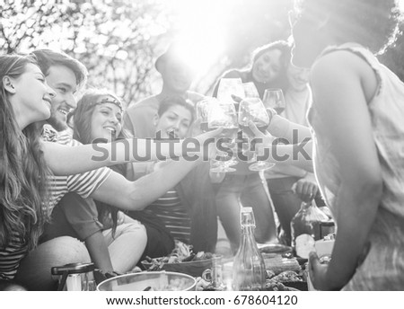 Happy friends cheering with wine glasses at pic-nic lunch outdoor - Young students having fun doing a toast and eating in nature - Food and youth concept - Focus on right bottom hand - Vintage filter