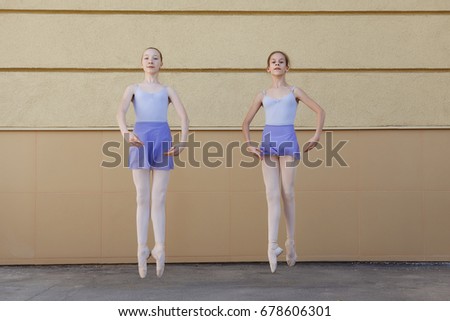 Ballet dancers dancing on street. Young ballerinas jump on yellow background full length