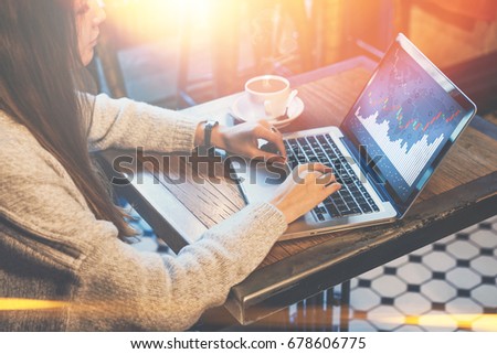 Young businesswoman sitting at table in coffee shop and typing on laptop. Graphics and charts, diagrams on computer screen. Woman analyzing data. Student learning online. Online marketing, education