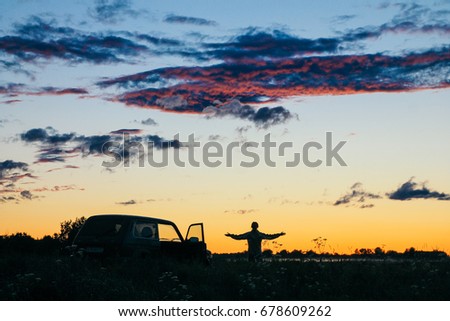 
Beautiful summer rural landscape with forest, meadow and mist at sunset. A young girl is going by car to watch the sunset
