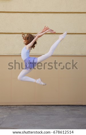 Ballet dancer dancing on street. Young ballerina jump on yellow background full length