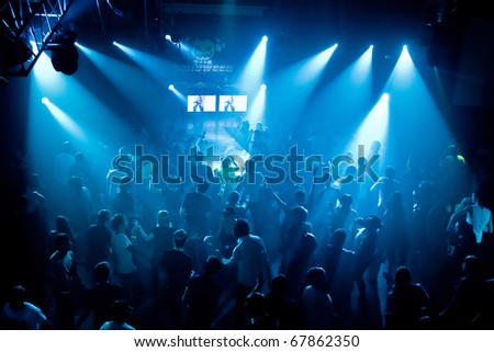 Dancing people in an underground club, blue stage light.