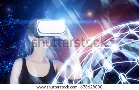 Close up of a blond girl in a black tank top wearing VR glasses and standing against a dark blue background with a network hologram Toned image double exposure Elements of this image furnished by NASA
