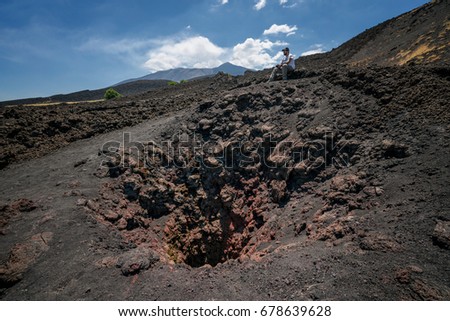 young man hiker looks the Etna's Valley near an old crater during a trekking day