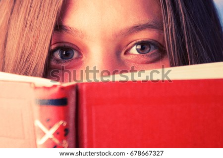 smiling girl with a book looking over book cover