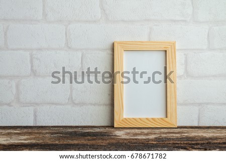 Photo frame on old wooden table over white brick wallpaper background