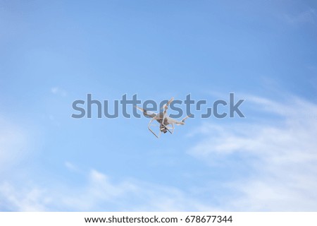 Quad copter or drone holds video using a digital camera on the blue sky background