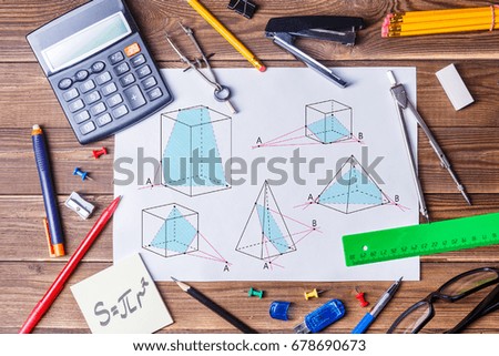 Album sheet with geometry pictures and student material on wooden table. Top view