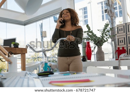 Happy businessman talking on smart phone while standing in office