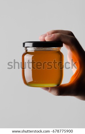 Honey Jar Mock-Up - Male hands holding a honey jar on a gray background