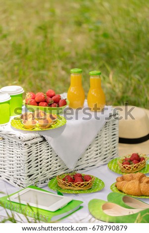 Summer time: picnic on the grass - coffee and croissants, juice and berries. Selective focus.