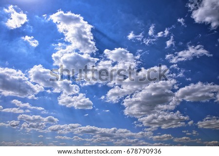 The blue sky in white clouds, through the clouds the rays of the sun