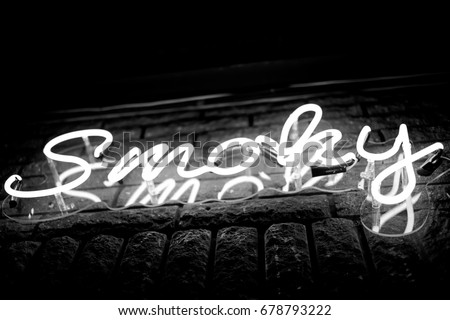 Neon inscription SMOKY on the wall. Neon inscription SMOKY in different colors. Multicolored neon inscription SMOKY on dark background