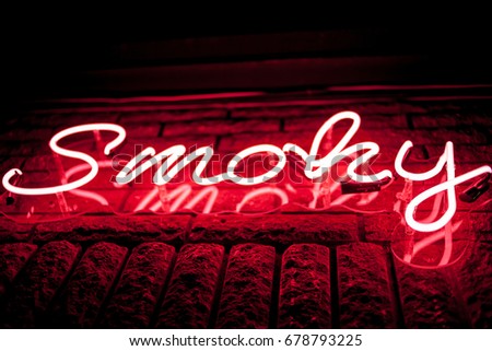 Neon inscription SMOKY on the wall. Neon inscription SMOKY in different colors. Multicolored neon inscription SMOKY on dark background