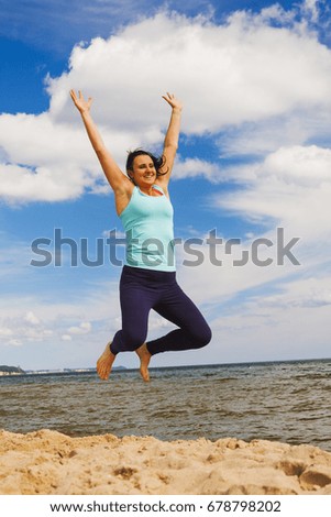attractive young girl jumping on a beach in the summer