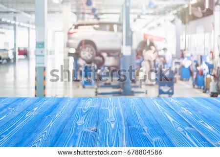 Empty blue wooden table free space and blurred background of car technician repairing the car in the shop, garage or service station. 