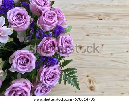 Purple roses bouquet on wooden floor with space for writing
