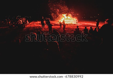 People sitting by he big fire during summer darkness night