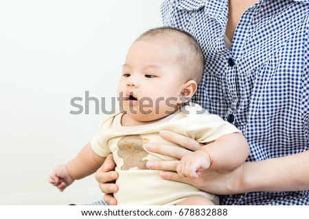 Portrait of an asian mother hugging her cute little baby on eva foam indoors