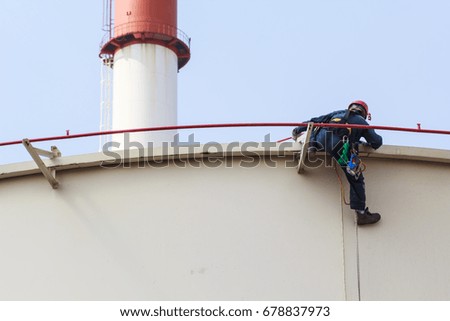 Male worker sitting on fire water tube rope access of inspection storage tank