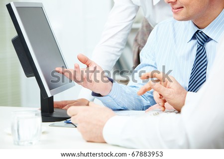 Image of young businessman hand pointing at computer monitor while making presentation