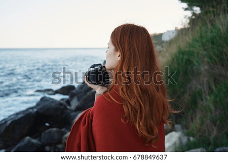 Woman in a plaid holds the camera and looks at the sea with the sunset                               