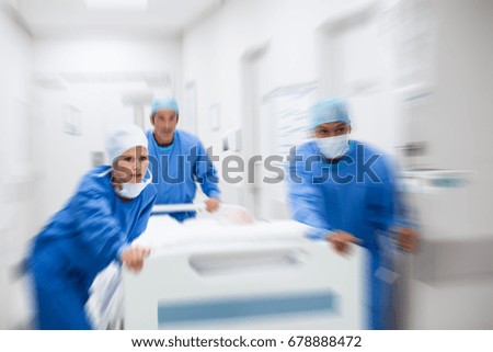 Nurse and doctor in a hurry taking patient to operation theatre. Patient on hospital bed pushed from surgeon to emergency theatre. Team of doctors and surgeon rushing patient. Royalty-Free Stock Photo #678888472