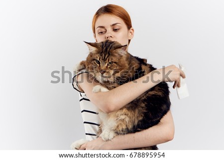Young beautiful woman on a light background holds a cat.