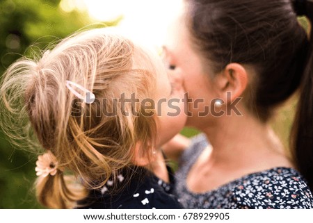 Young mother in nature holding little daughter in the arms.