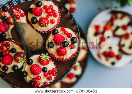 Muffins with cream and berries lie on a two-level stand in the zone of the wedding banquet. Top view