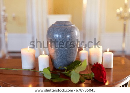 funeral and mourning concept - red rose and cremation urn with burning candles on table in church Royalty-Free Stock Photo #678985045
