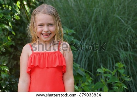 adorable school age girl playing outside in sprinkler 