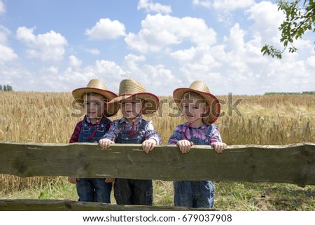 three little cowboys outdoors in a field