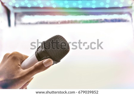 Hand holing digital wireless Microphone on blur white lighting background.