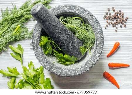 Spices, fresh greens and mortar on wood background