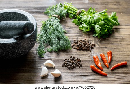 Spices, greenery and mortar on wood table