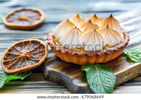 Tartlet with lemon cream and citrus chips on the old wooden table, selective focus.