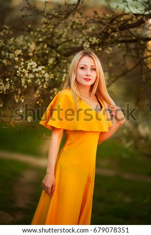 Girl in a yellow dress in a flowery garden