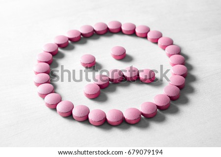 Clinical depression, mental illness and disorder or bad health services concept. Sad smiley face made from pills, medicine and tablets on wooden table. Dissatisfied and unhappy icon.