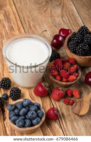Milk with and berries on a wooden table background, side top view.
