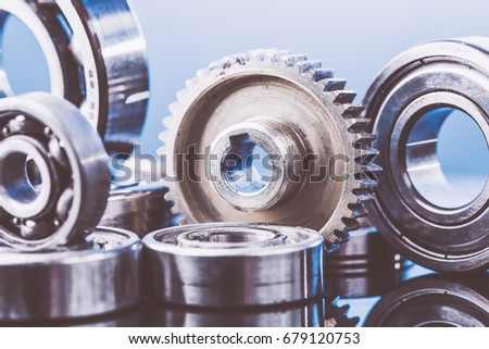 Group of various ball bearings and gears close up on nice blue background with reflections. Toned.