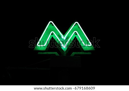 Night view of an illuminated green neon letter "M" - standing for metro (subway or underground)